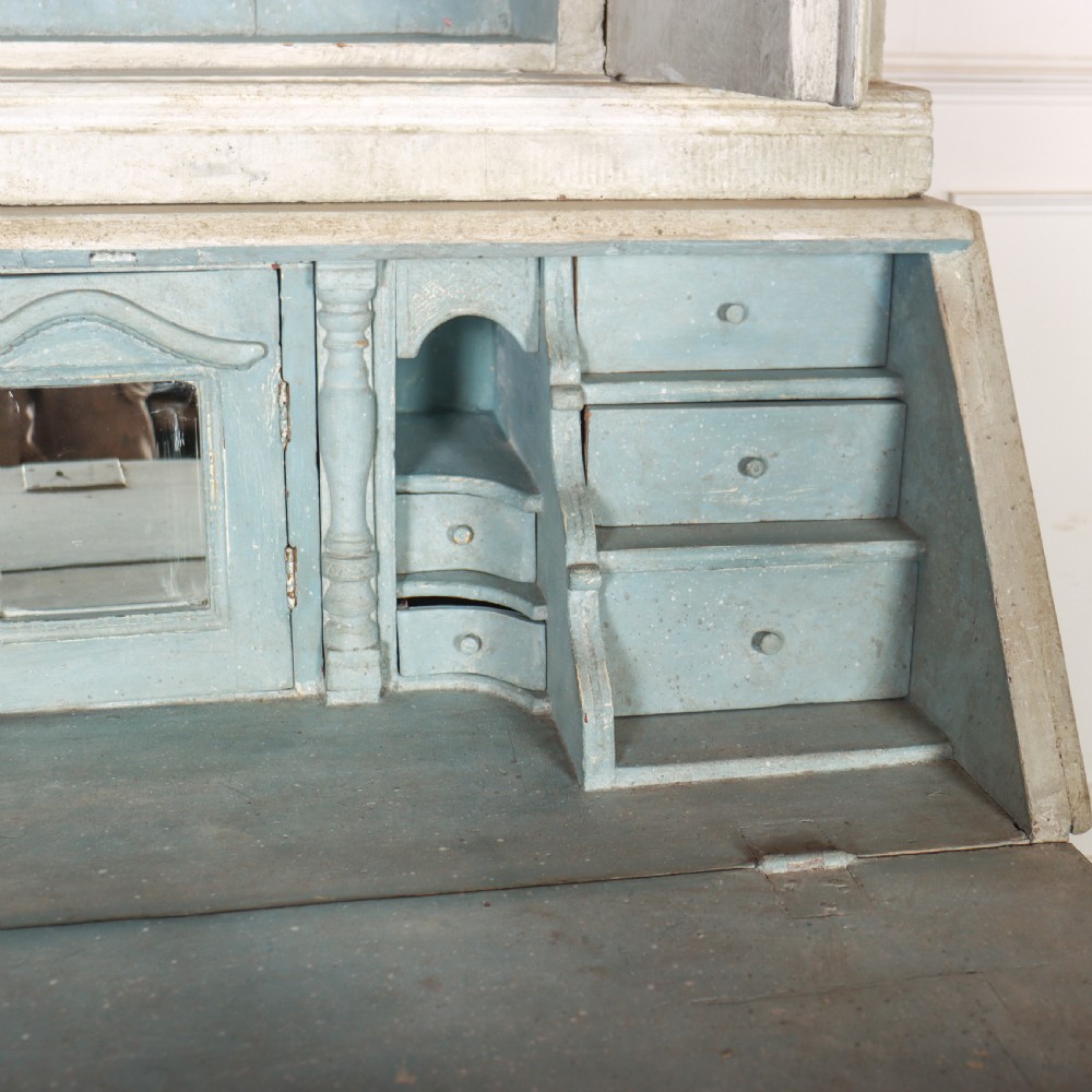 An off-white painted Danish bureau bookcase with a gallery-topped upper cupboard, stepped side drawers, a slant-front desk, and lower drawers fitted with brass lion-head ring handles. View XII