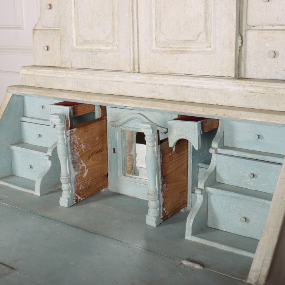 An off-white painted Danish bureau bookcase with a gallery-topped upper cupboard, stepped side drawers, a slant-front desk, and lower drawers fitted with brass lion-head ring handles. View XIV