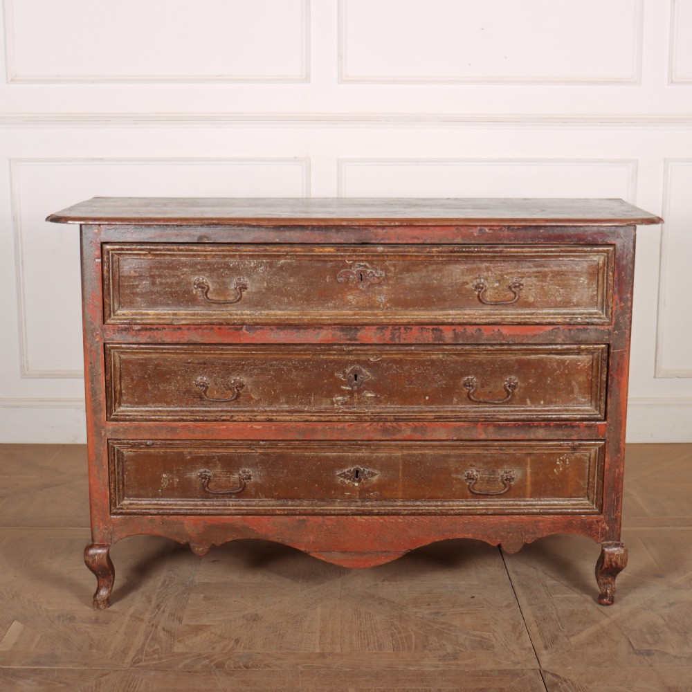 An antique three-drawer Italian commode featuring a painted red and brown finish, carved cabriole legs, and metal drop handles.