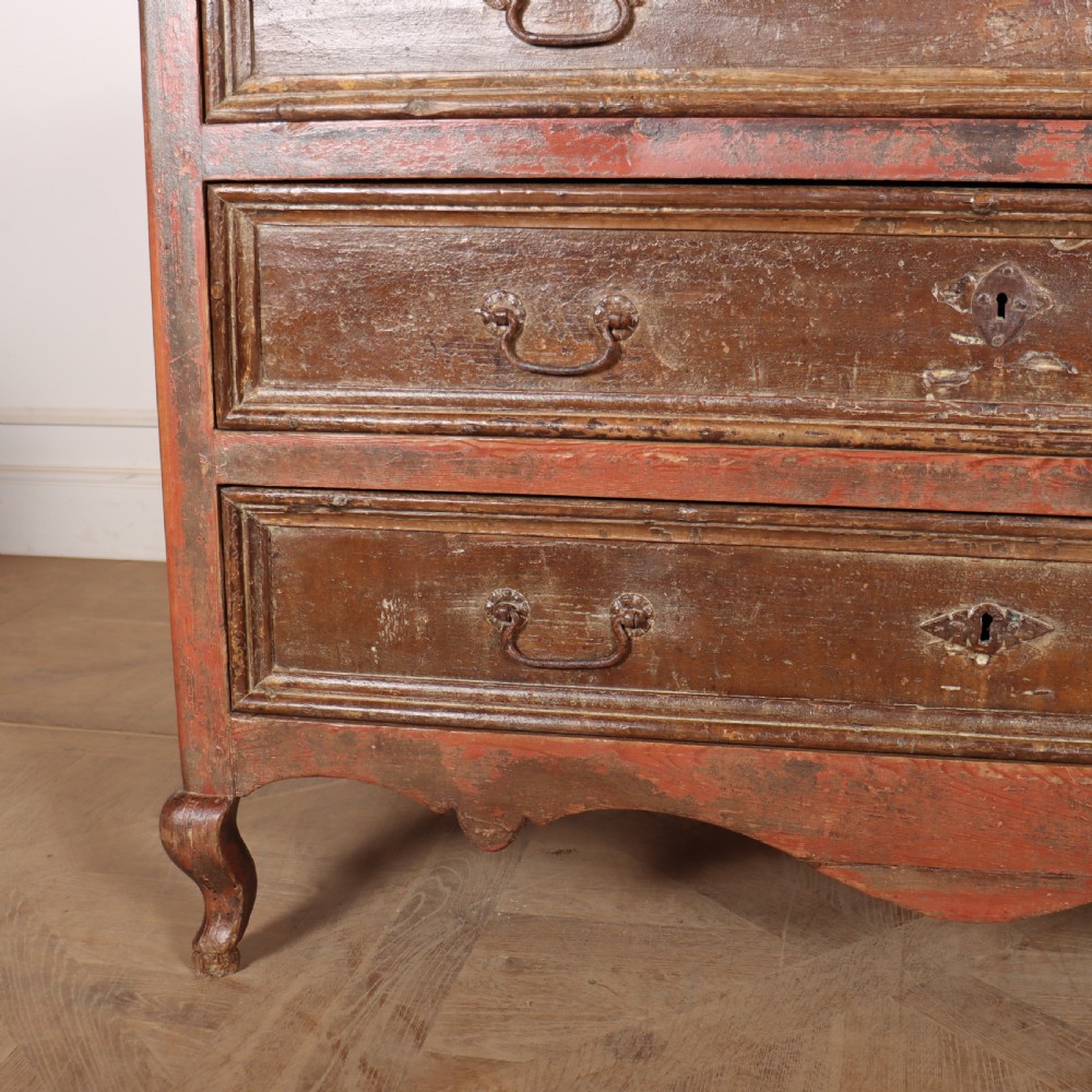 An antique three-drawer Italian commode featuring a painted red and brown finish, carved cabriole legs, and metal drop handles. View III