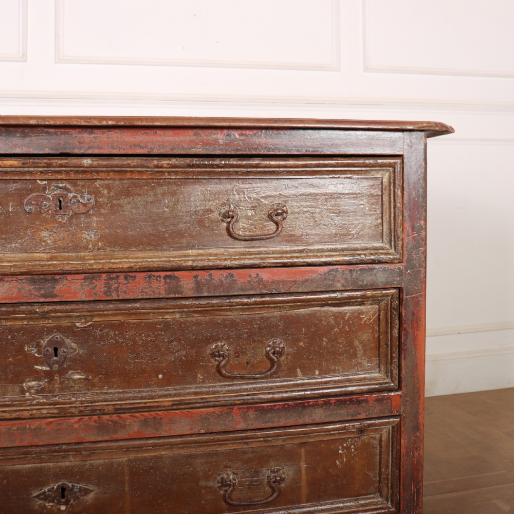 An antique three-drawer Italian commode featuring a painted red and brown finish, carved cabriole legs, and metal drop handles. View V