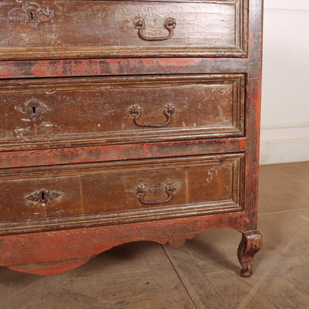 An antique three-drawer Italian commode featuring a painted red and brown finish, carved cabriole legs, and metal drop handles. View VI