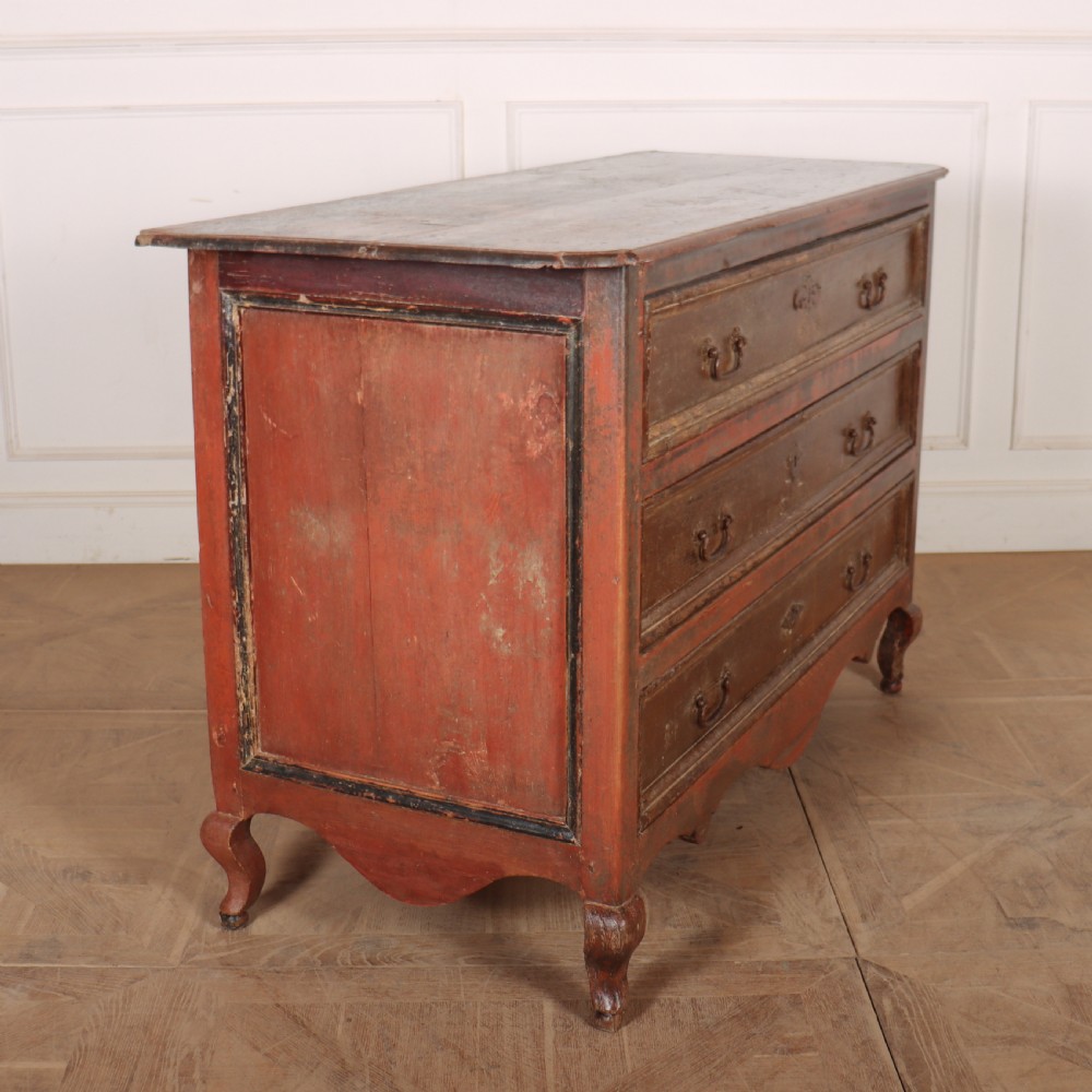 An antique three-drawer Italian commode featuring a painted red and brown finish, carved cabriole legs, and metal drop handles. View VII