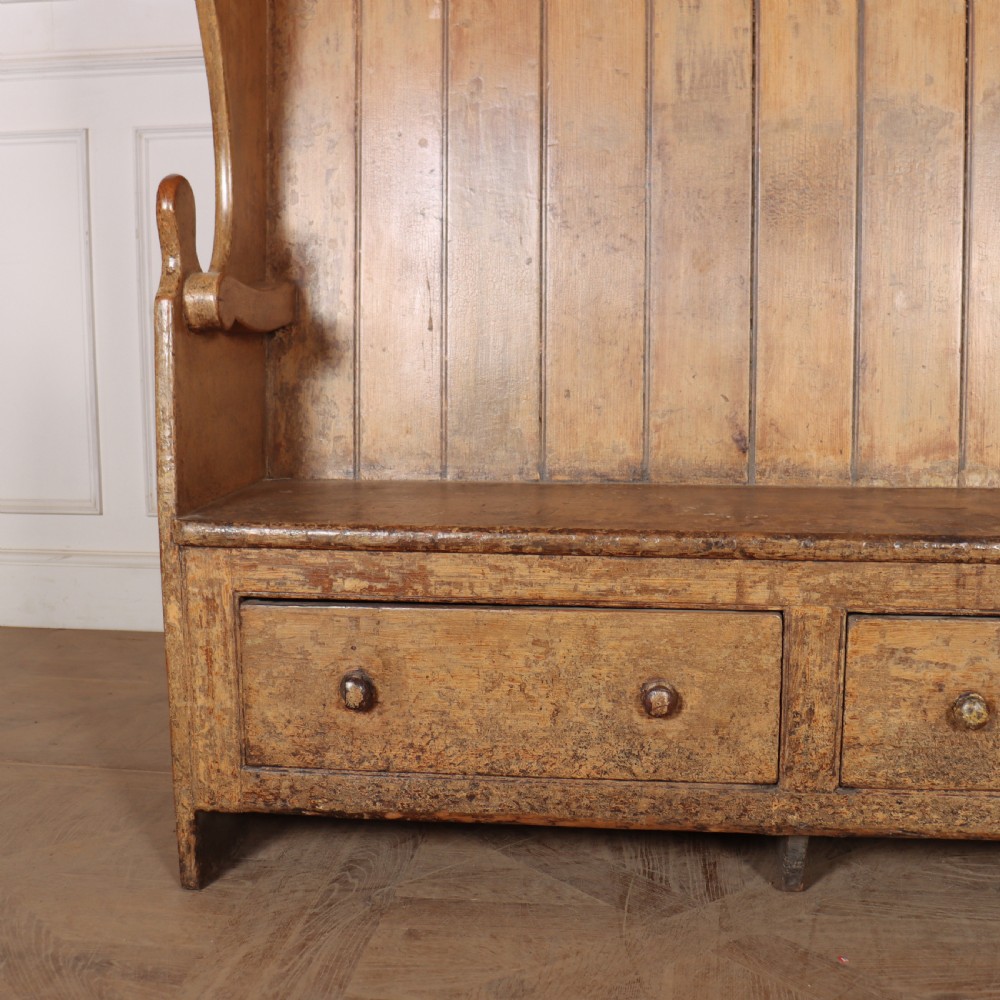An antique high-backed wooden tavern settle featuring vertical board panelling, shaped side wings, two base drawers, and a distressed painted finish. View II
