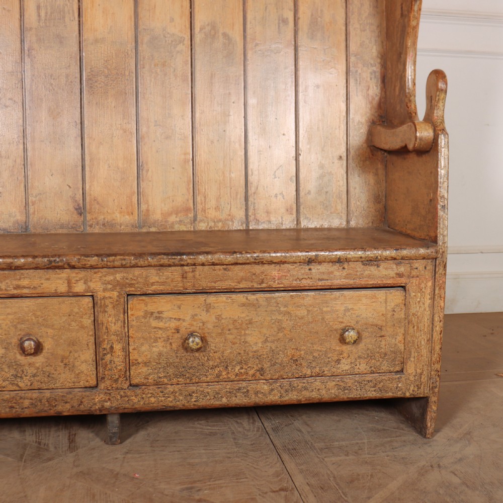 An antique high-backed wooden tavern settle featuring vertical board panelling, shaped side wings, two base drawers, and a distressed painted finish. View III