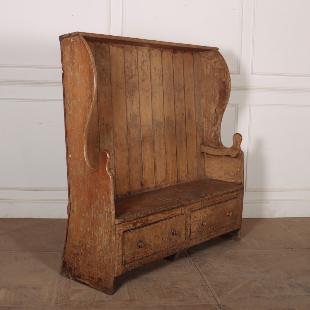 An antique high-backed wooden tavern settle featuring vertical board panelling, shaped side wings, two base drawers, and a distressed painted finish. View IV