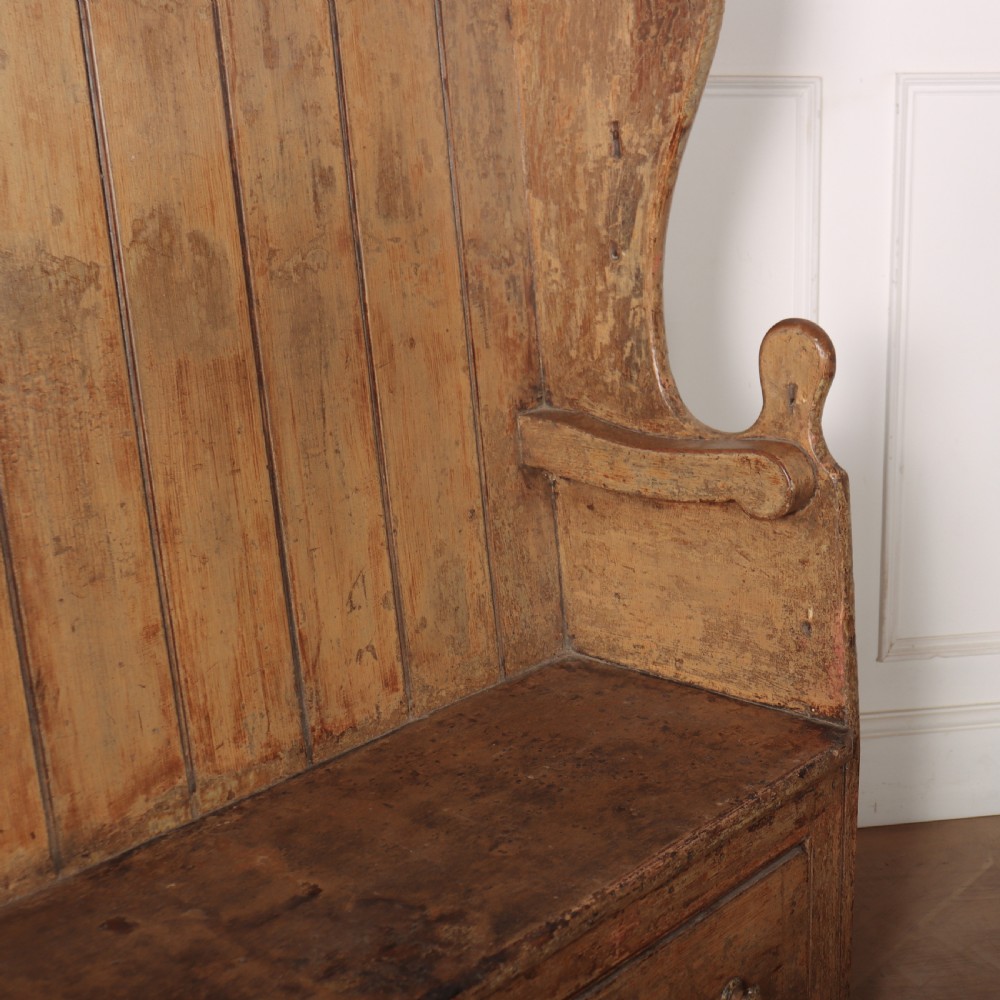 An antique high-backed wooden tavern settle featuring vertical board panelling, shaped side wings, two base drawers, and a distressed painted finish. View V
