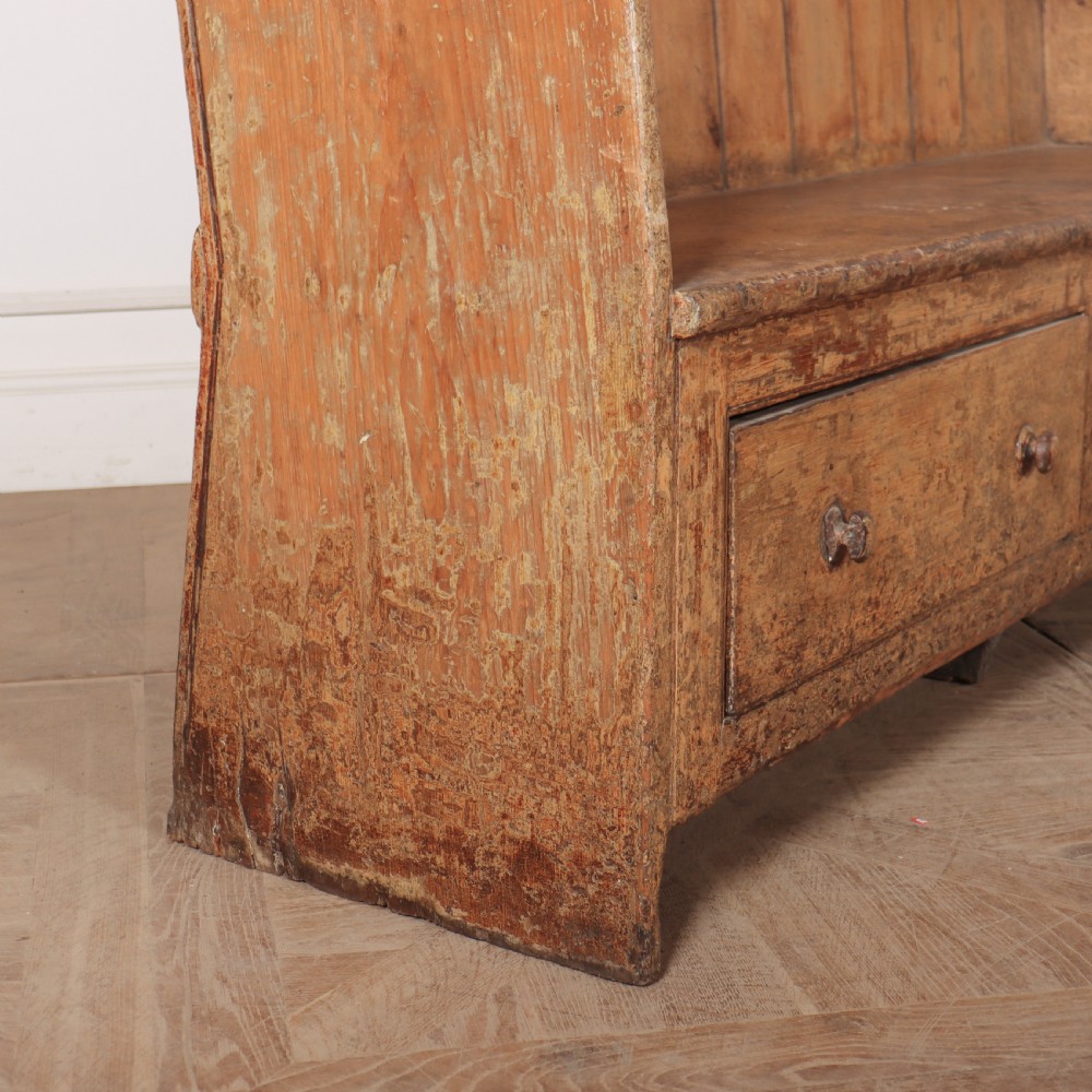 An antique high-backed wooden tavern settle featuring vertical board panelling, shaped side wings, two base drawers, and a distressed painted finish. View VI