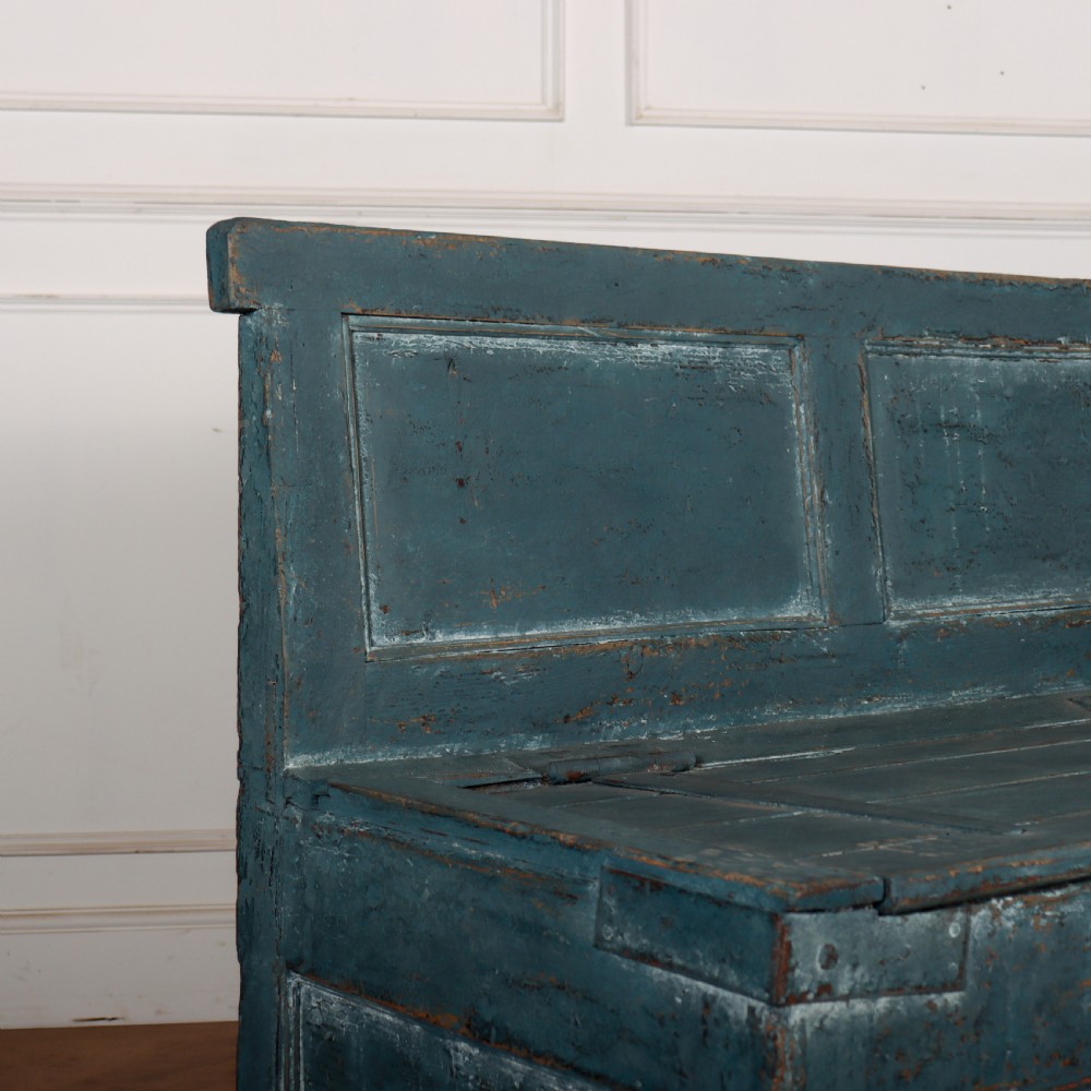 A long antique pine settle bench painted in distressed teal blue, featuring a four-panel backrest and a hinged seat lid. View IV