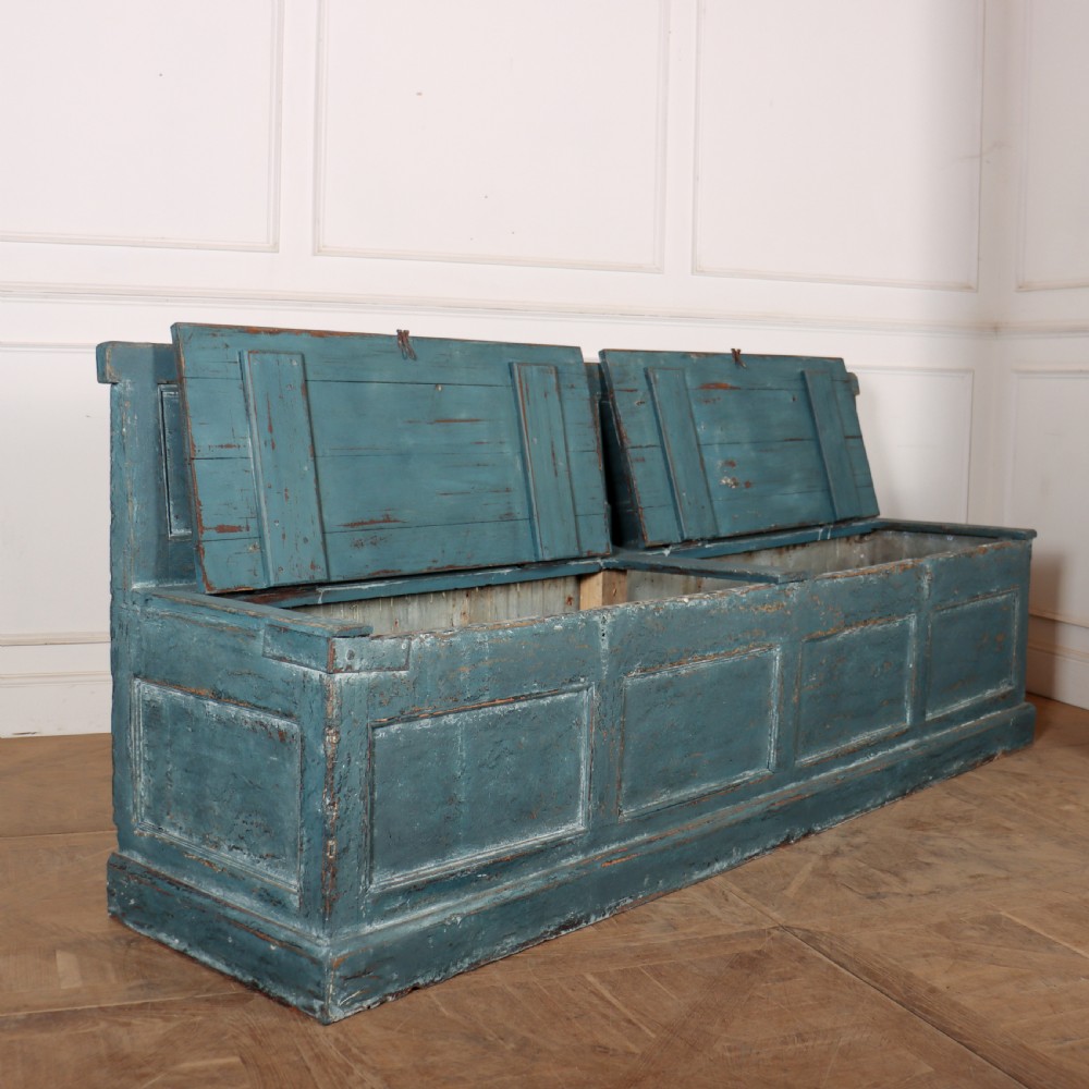 A long antique pine settle bench painted in distressed teal blue, featuring a four-panel backrest and a hinged seat lid. View VII