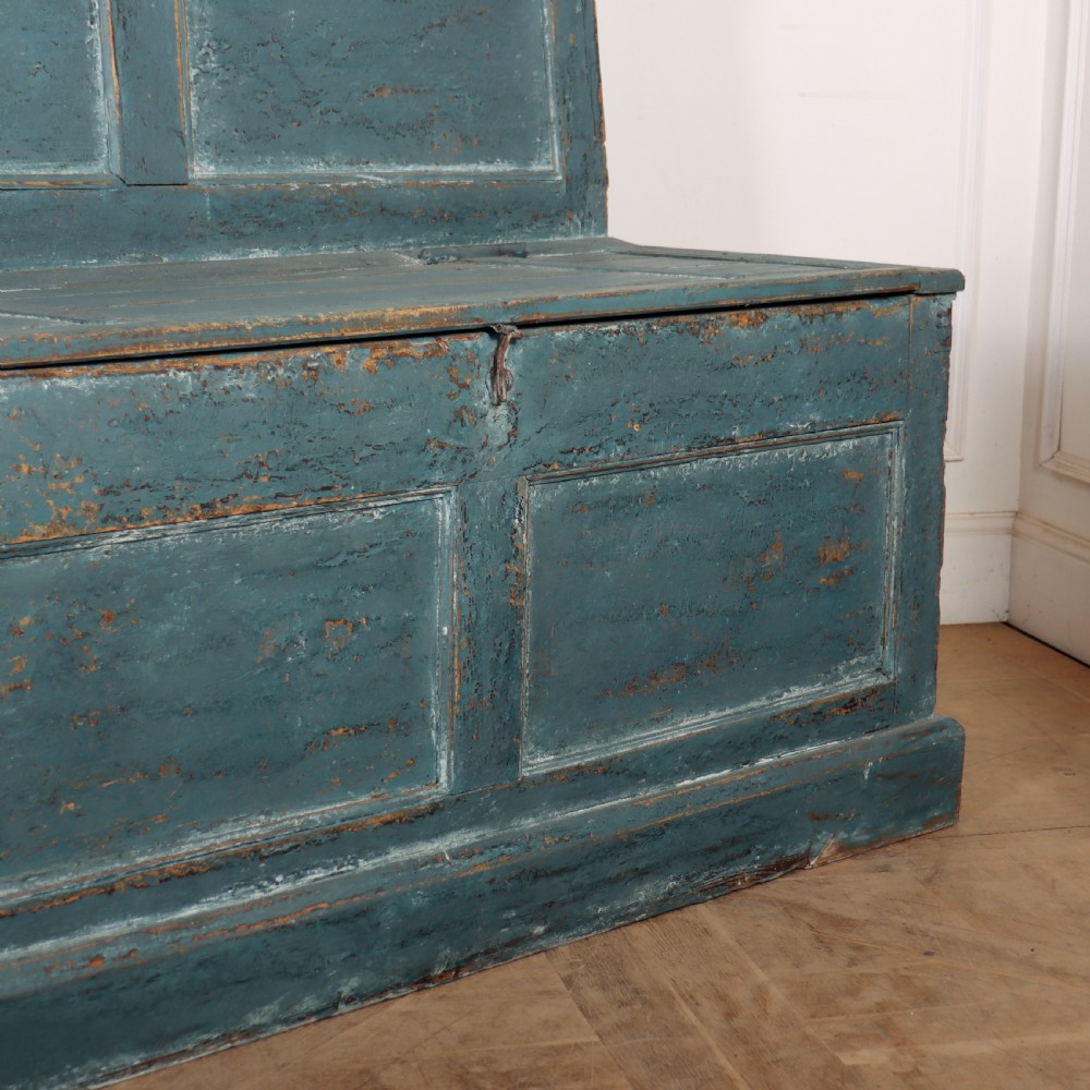 A long antique pine settle bench painted in distressed teal blue, featuring a four-panel backrest and a hinged seat lid. View VIII