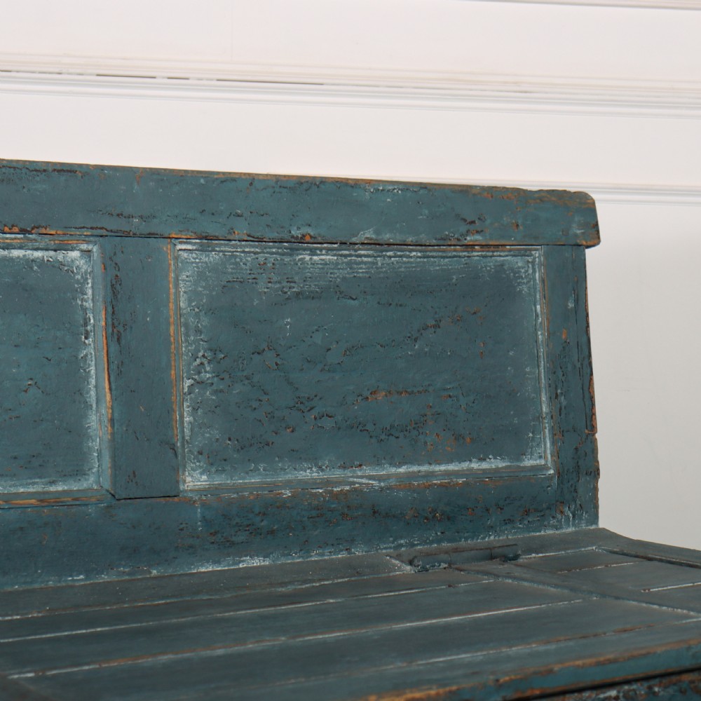 A long antique pine settle bench painted in distressed teal blue, featuring a four-panel backrest and a hinged seat lid. View IX