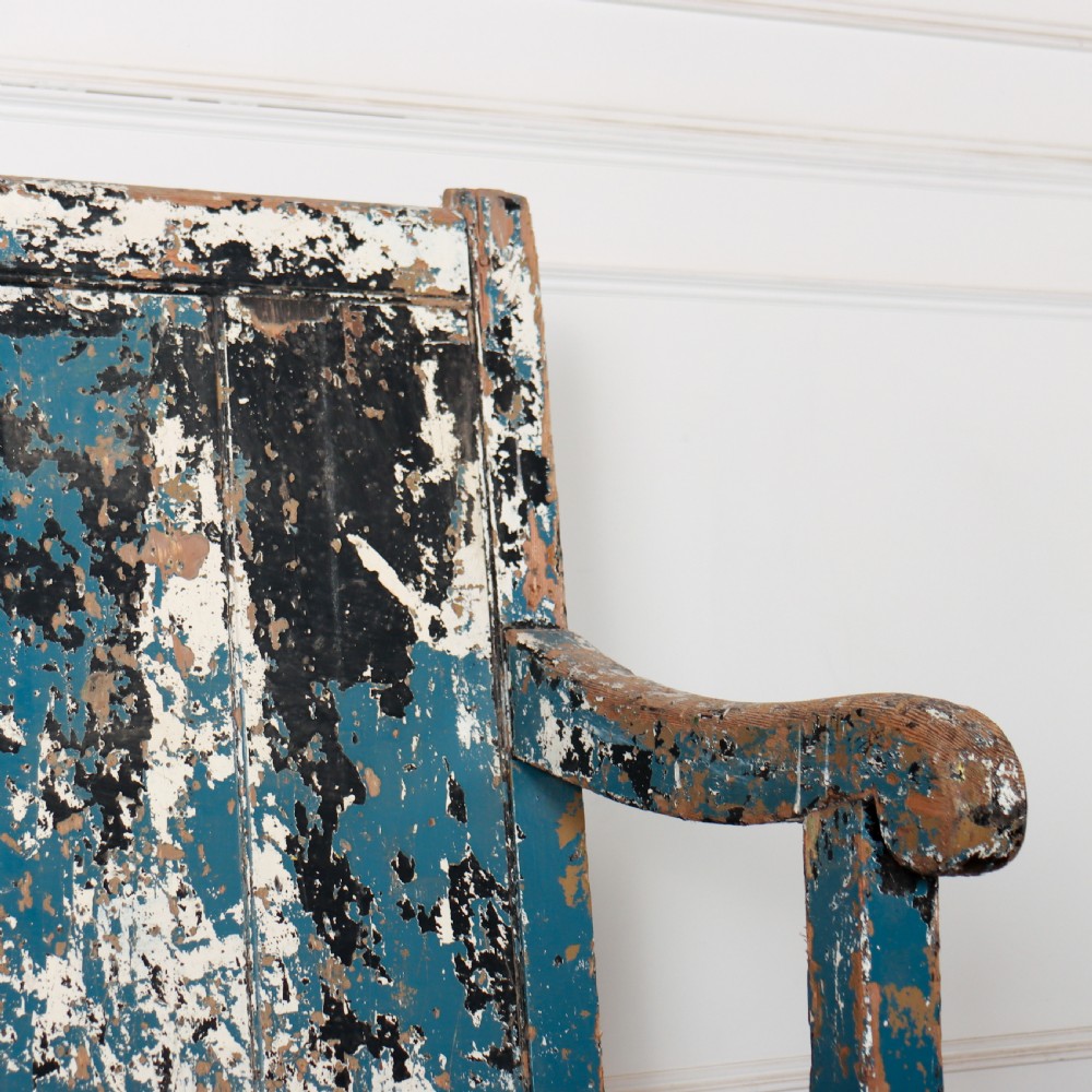An antique English high back wooden settle bench featuring distressed layers of blue and cream paint with visible exposed timber. View V