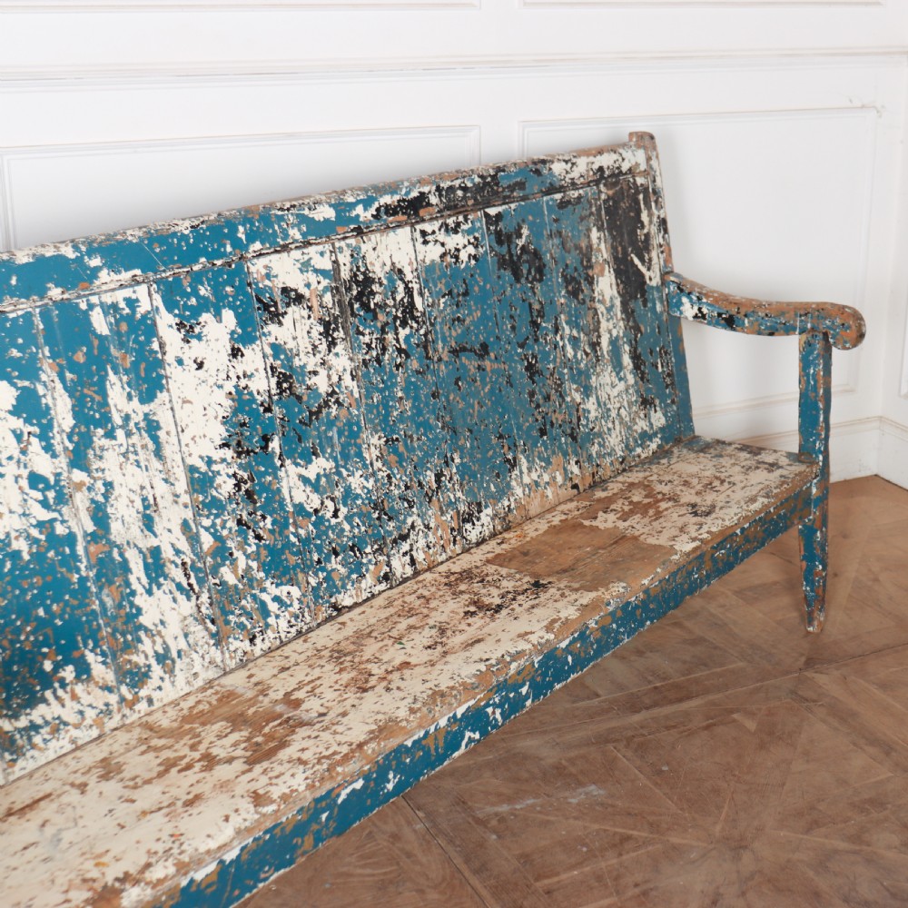 An antique English high back wooden settle bench featuring distressed layers of blue and cream paint with visible exposed timber. View VII