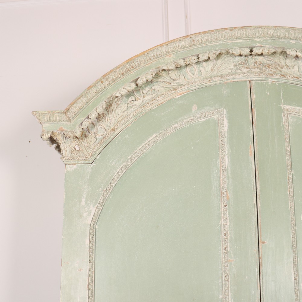 A 19th-century green painted wooden wardrobe featuring an arched carved cresting, double panelled doors, and a distressed finish. View II