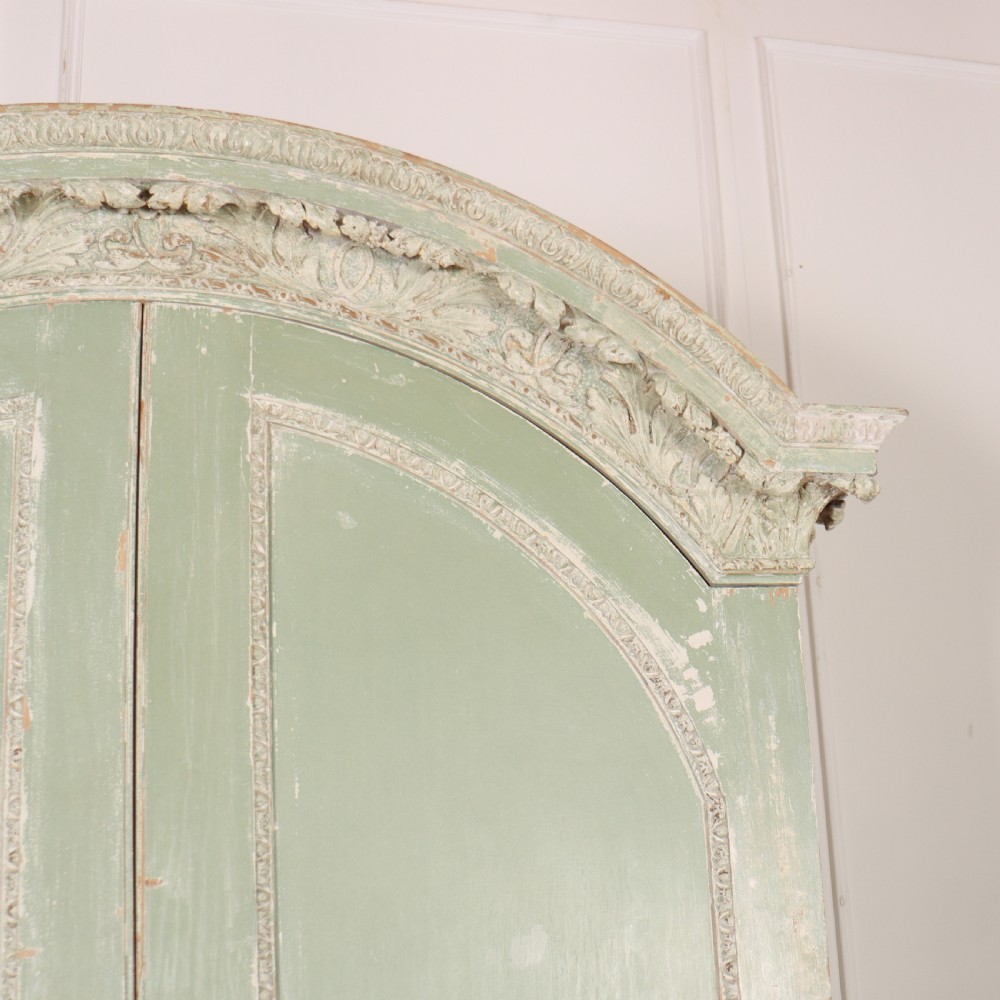 A 19th-century green painted wooden wardrobe featuring an arched carved cresting, double panelled doors, and a distressed finish. View III