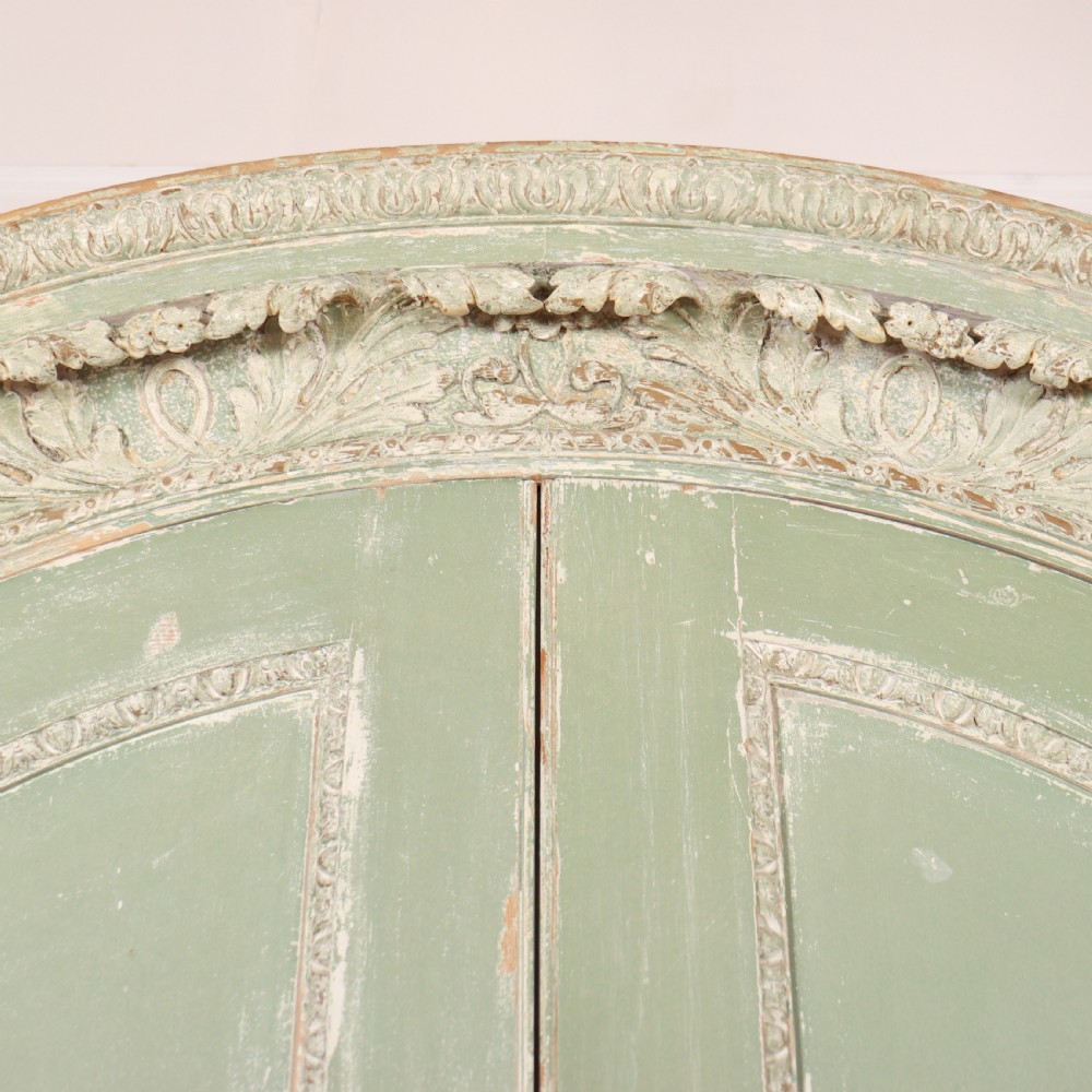 A 19th-century green painted wooden wardrobe featuring an arched carved cresting, double panelled doors, and a distressed finish. View IV