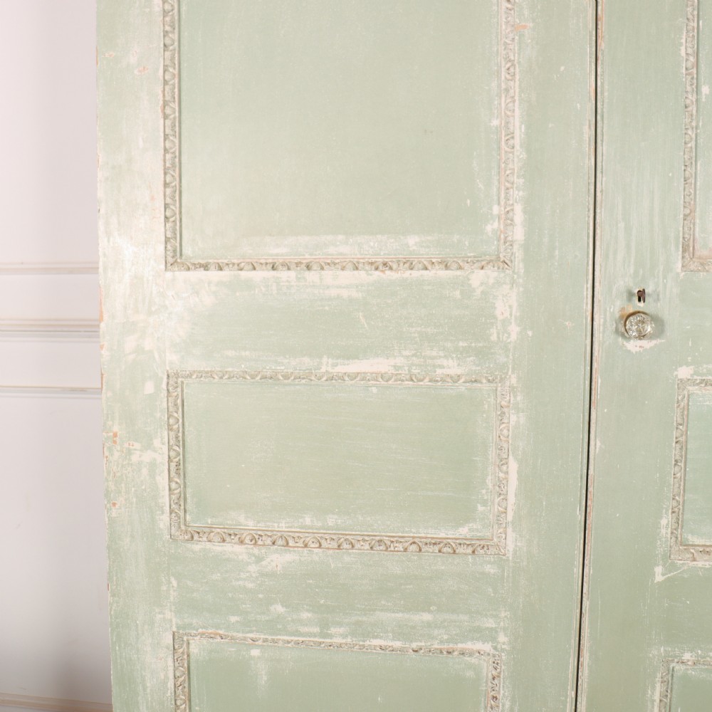 A 19th-century green painted wooden wardrobe featuring an arched carved cresting, double panelled doors, and a distressed finish. View VI