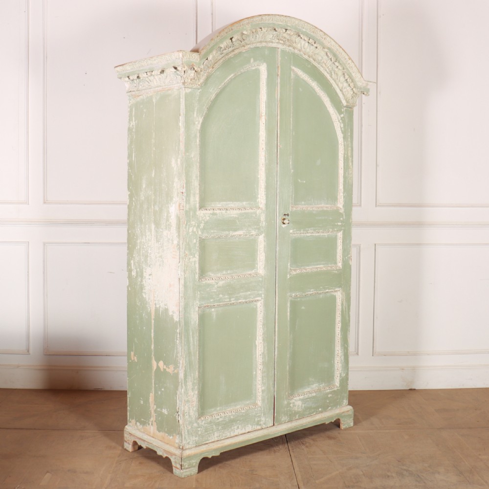 A 19th-century green painted wooden wardrobe featuring an arched carved cresting, double panelled doors, and a distressed finish. View IX