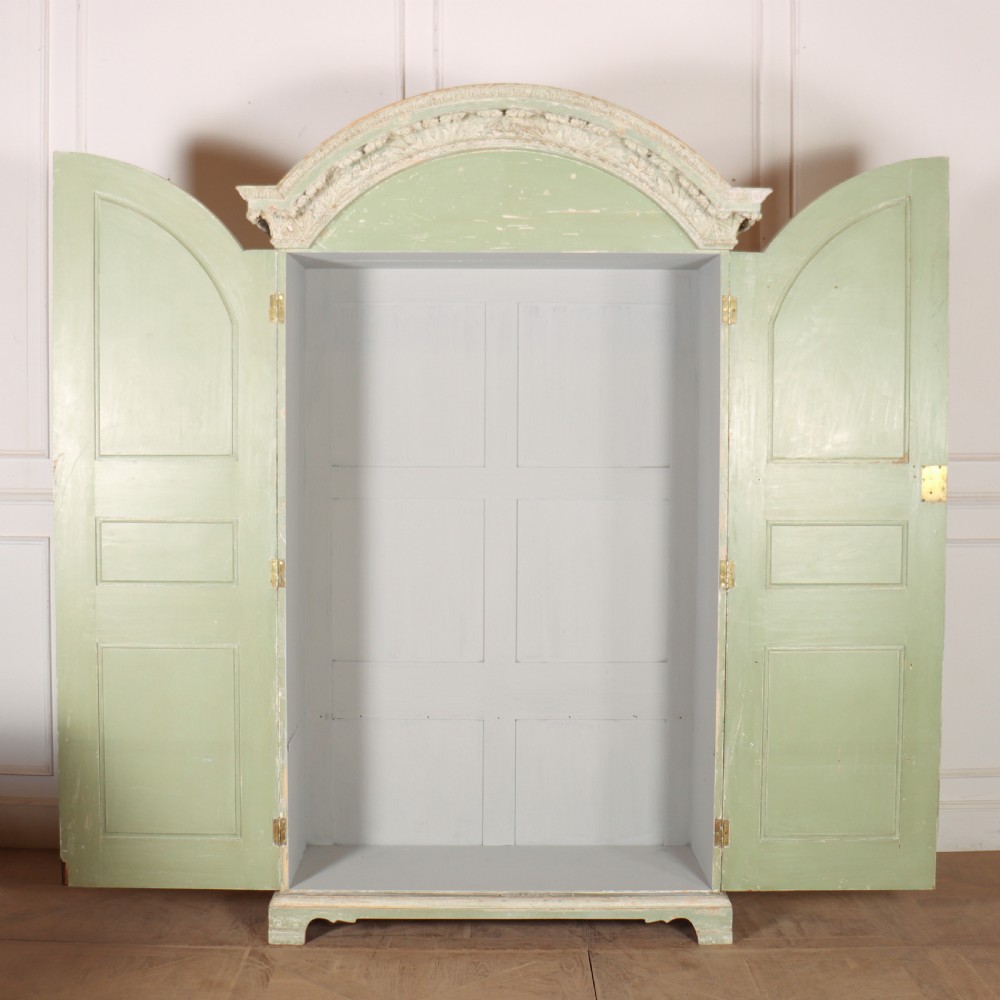 A 19th-century green painted wooden wardrobe featuring an arched carved cresting, double panelled doors, and a distressed finish. View XII