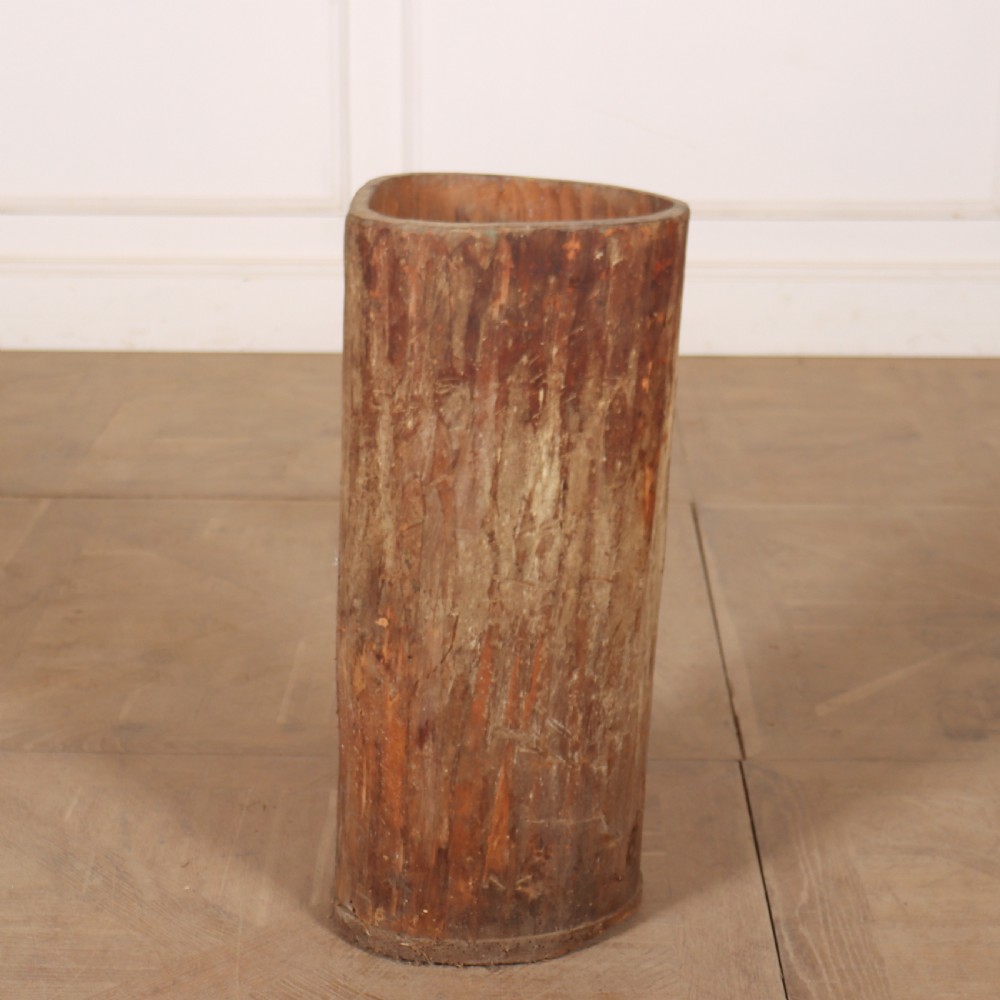 A cylindrical rustic vessel crafted from a hollowed-out tree trunk with weathered natural wood grain.