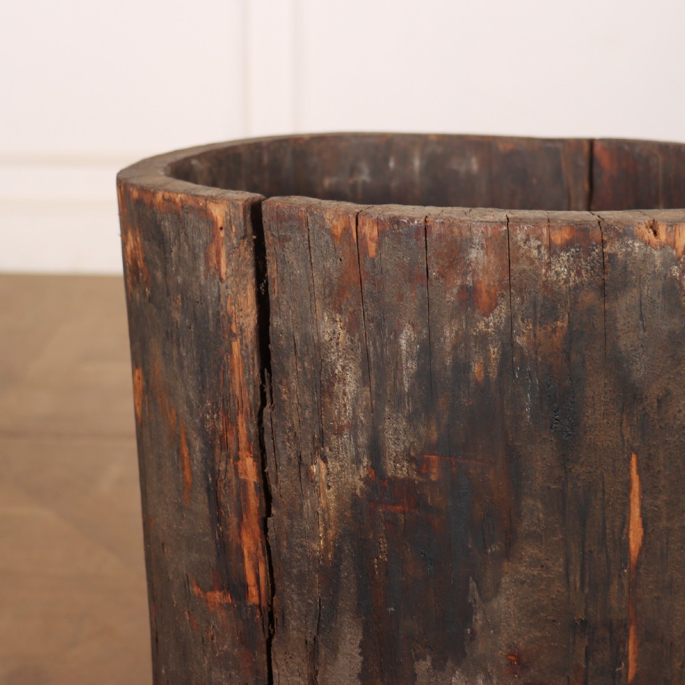 A vertical hollowed-out tree trunk displaying dark weathered timber with natural grain splits. View IV
