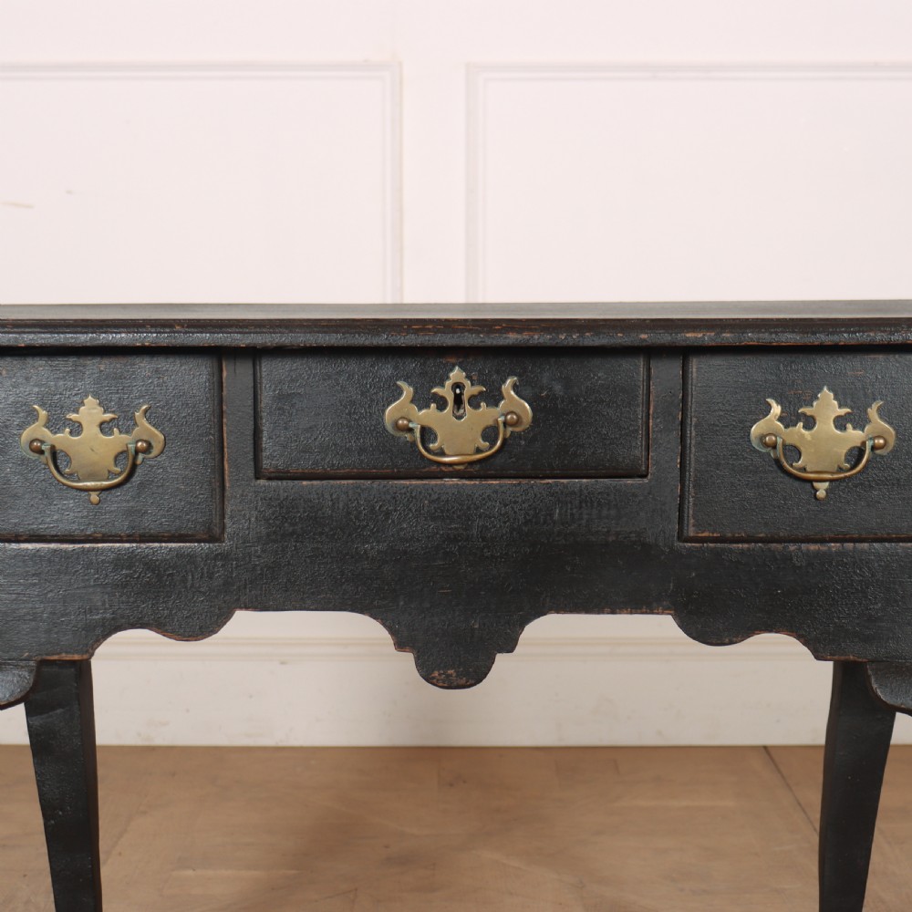 A black painted antique lowboy table featuring three drawers with brass batwing handles, a shaped apron, and cabriole legs. View II