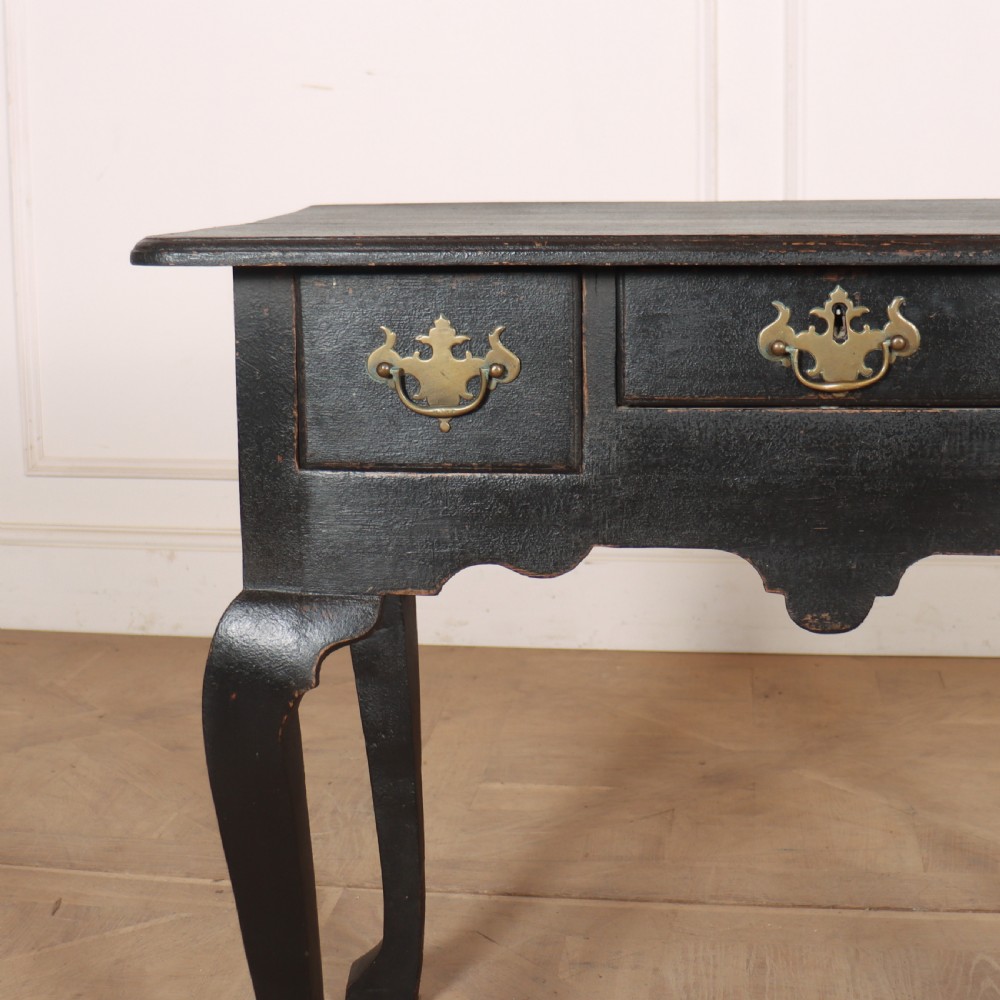 A black painted antique lowboy table featuring three drawers with brass batwing handles, a shaped apron, and cabriole legs. View VI