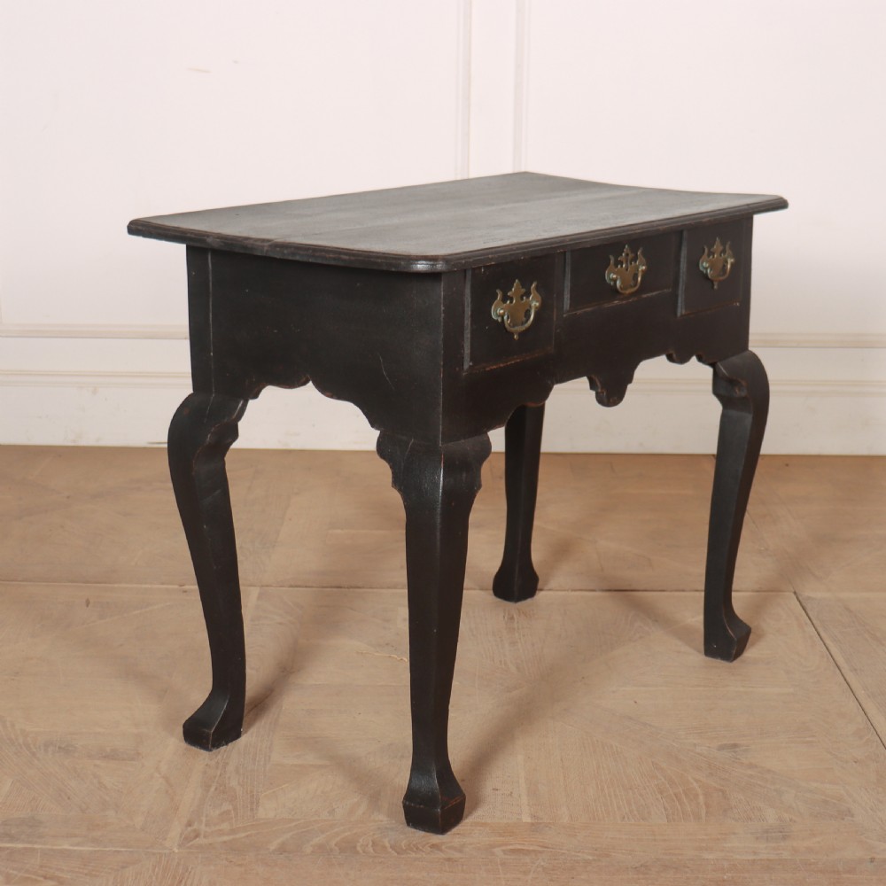 A black painted antique lowboy table featuring three drawers with brass batwing handles, a shaped apron, and cabriole legs. View VII
