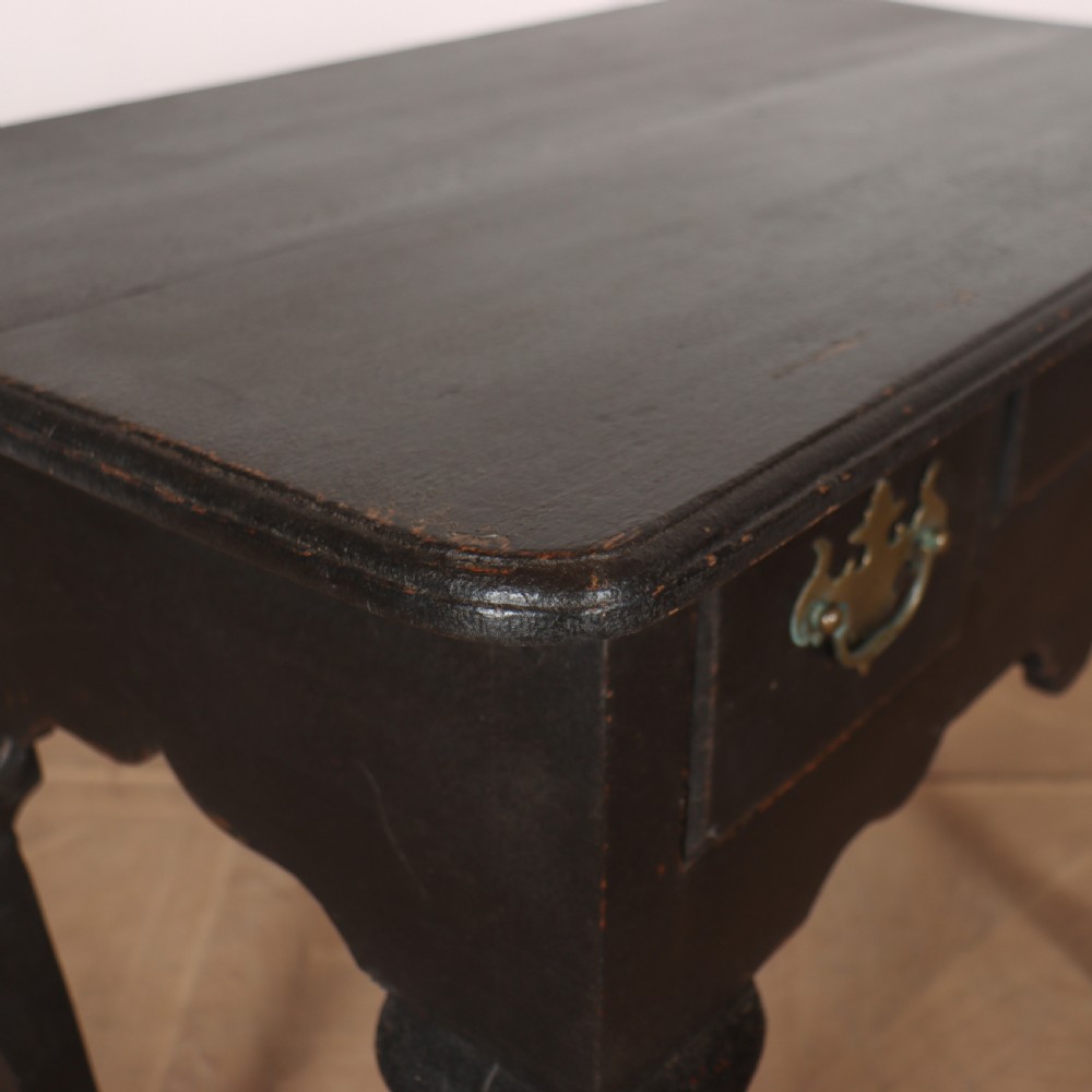 A black painted antique lowboy table featuring three drawers with brass batwing handles, a shaped apron, and cabriole legs. View IX