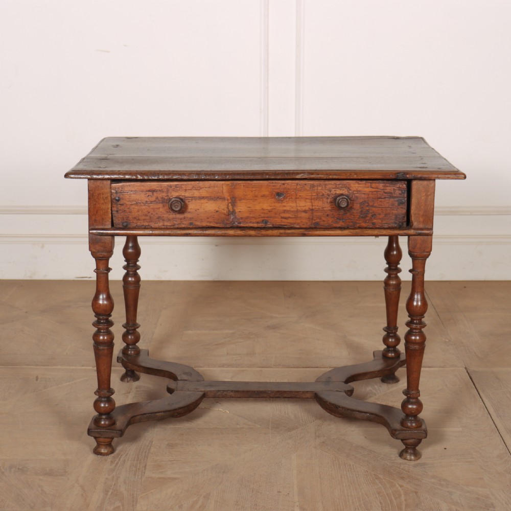 An 18th-century oak side table with a single frieze drawer, turned legs, wooden knobs, and a shaped lower stretcher.