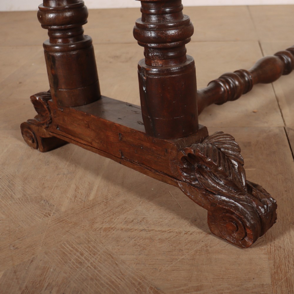 An antique dark walnut trestle table featuring turned baluster legs, carved scroll feet, and a turned central stretcher. View II