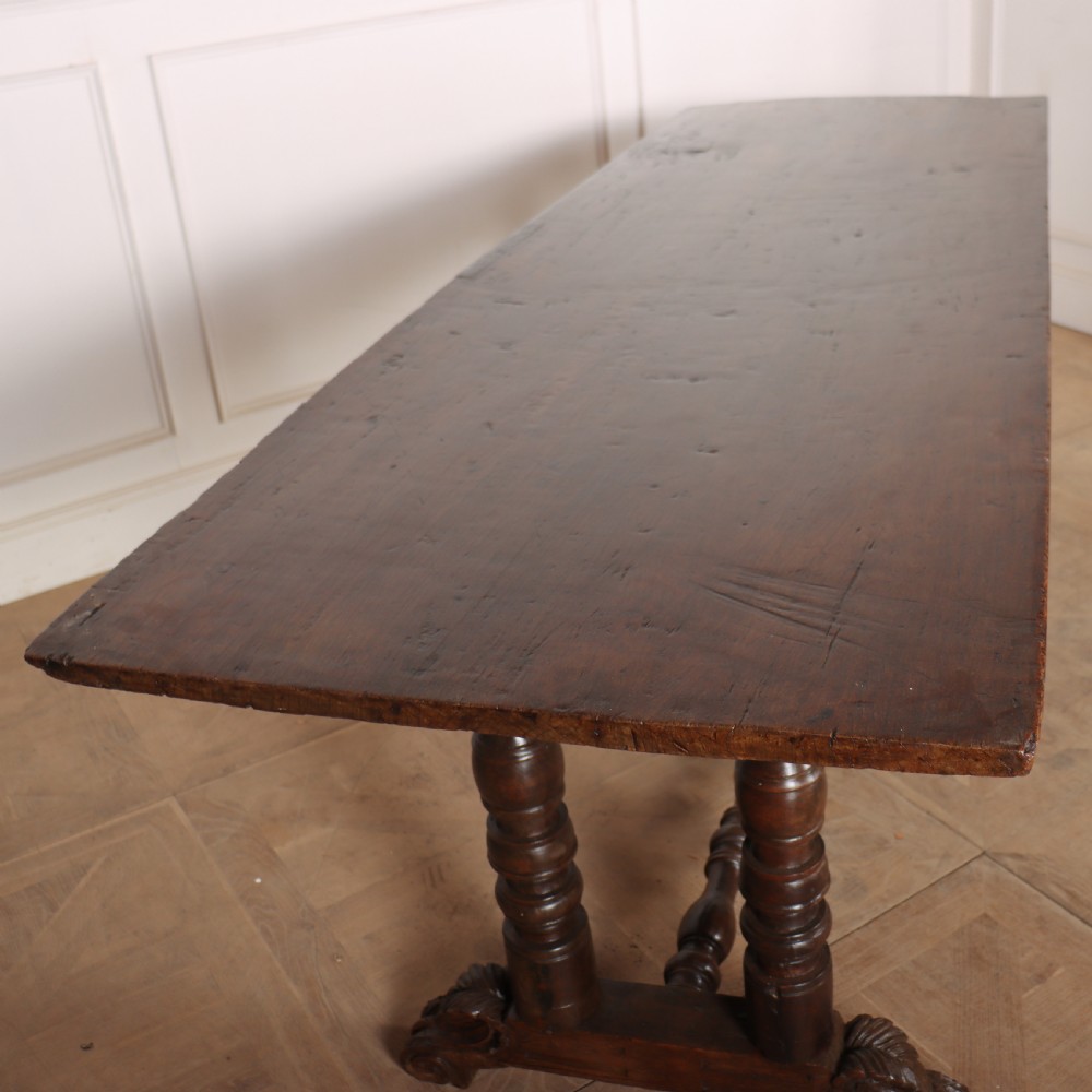 An antique dark walnut trestle table featuring turned baluster legs, carved scroll feet, and a turned central stretcher. View VI