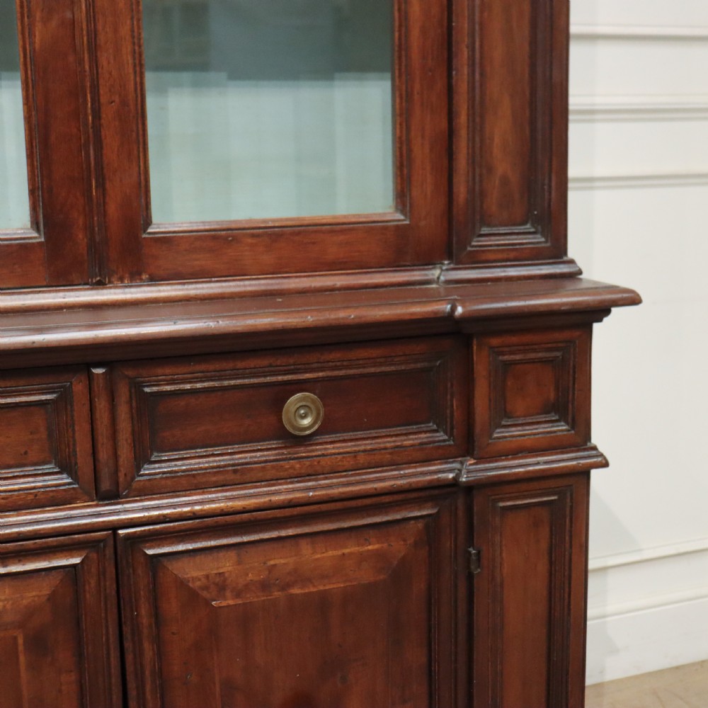 A large Italian dark walnut bookcase featuring four upper glass doors, four small drawers, and four fielded panel doors below. View VI
