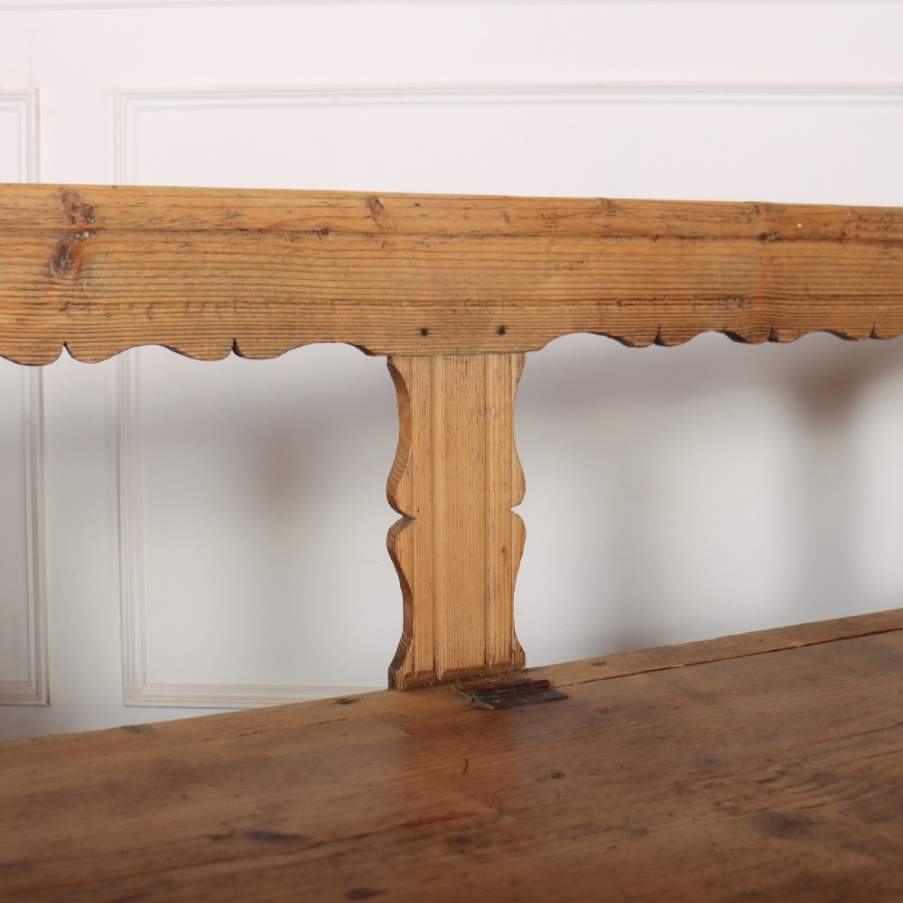 A nineteenth-century Swedish pine settle bench featuring open spindled side panels, a scalloped backrail, and a lift-top storage seat base. View VI
