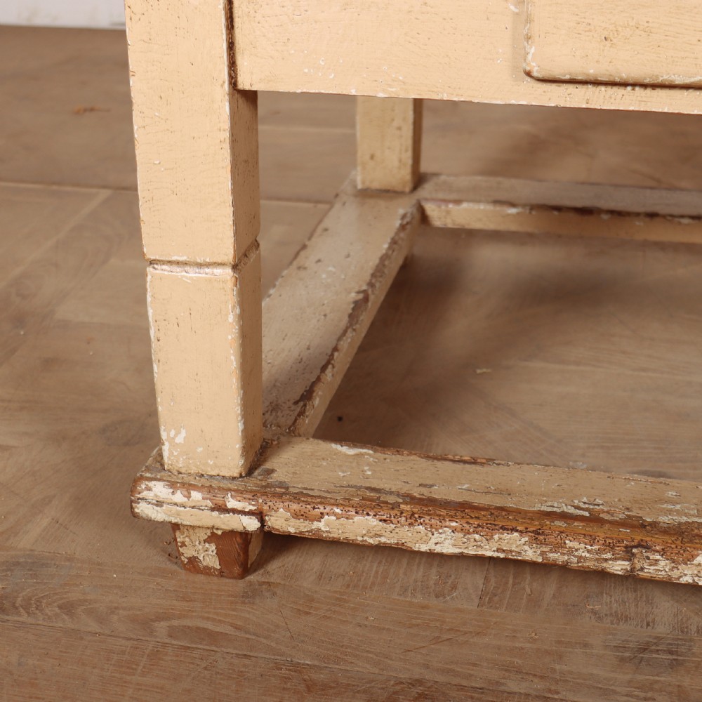 A rectangular low painted coffee table featuring a distressed cream paint finish, a single drawer with a metal drop handle, and a perimeter floor stretcher. View III