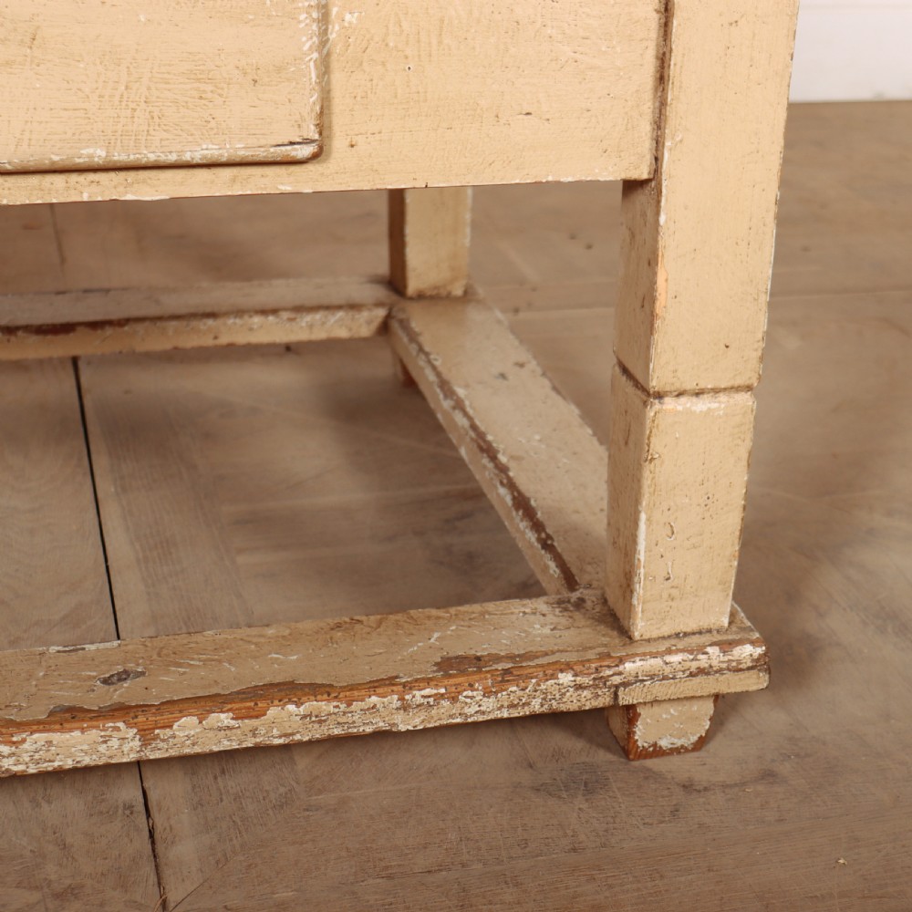 A rectangular low painted coffee table featuring a distressed cream paint finish, a single drawer with a metal drop handle, and a perimeter floor stretcher. View IV