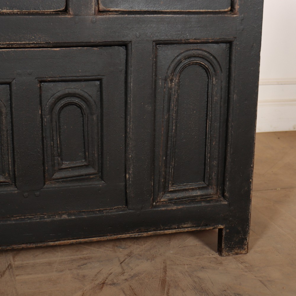 An 18th-century dark painted wooden dresser base featuring four frieze drawers above recessed cupboard doors decorated with geometric arch mouldings. View V