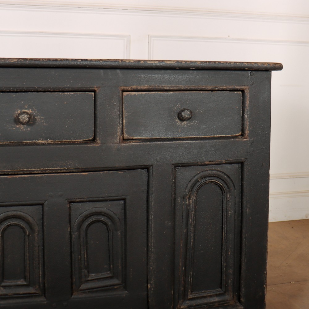 An 18th-century dark painted wooden dresser base featuring four frieze drawers above recessed cupboard doors decorated with geometric arch mouldings. View VI