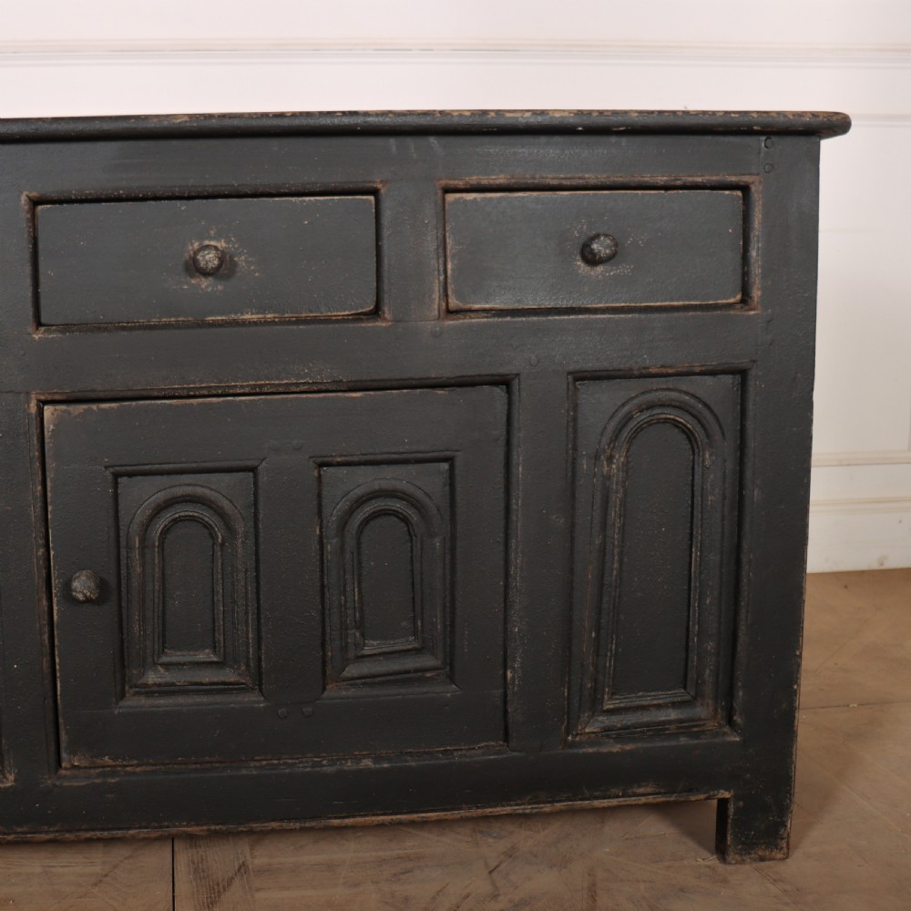 An 18th-century dark painted wooden dresser base featuring four frieze drawers above recessed cupboard doors decorated with geometric arch mouldings. View VII