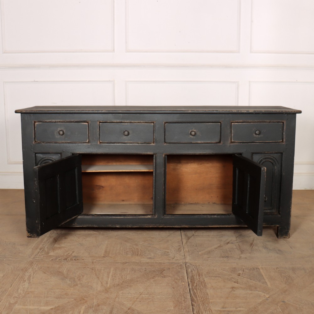 An 18th-century dark painted wooden dresser base featuring four frieze drawers above recessed cupboard doors decorated with geometric arch mouldings. View VIII