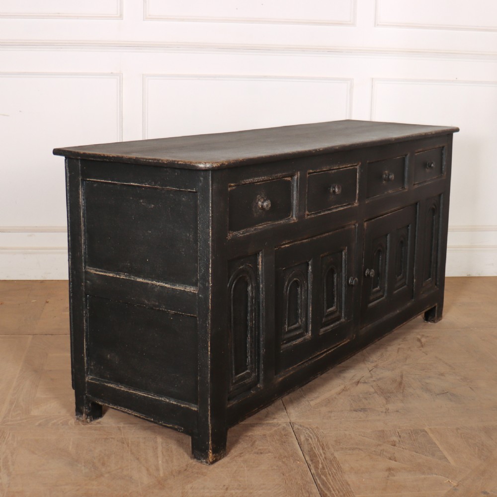 An 18th-century dark painted wooden dresser base featuring four frieze drawers above recessed cupboard doors decorated with geometric arch mouldings. View IX