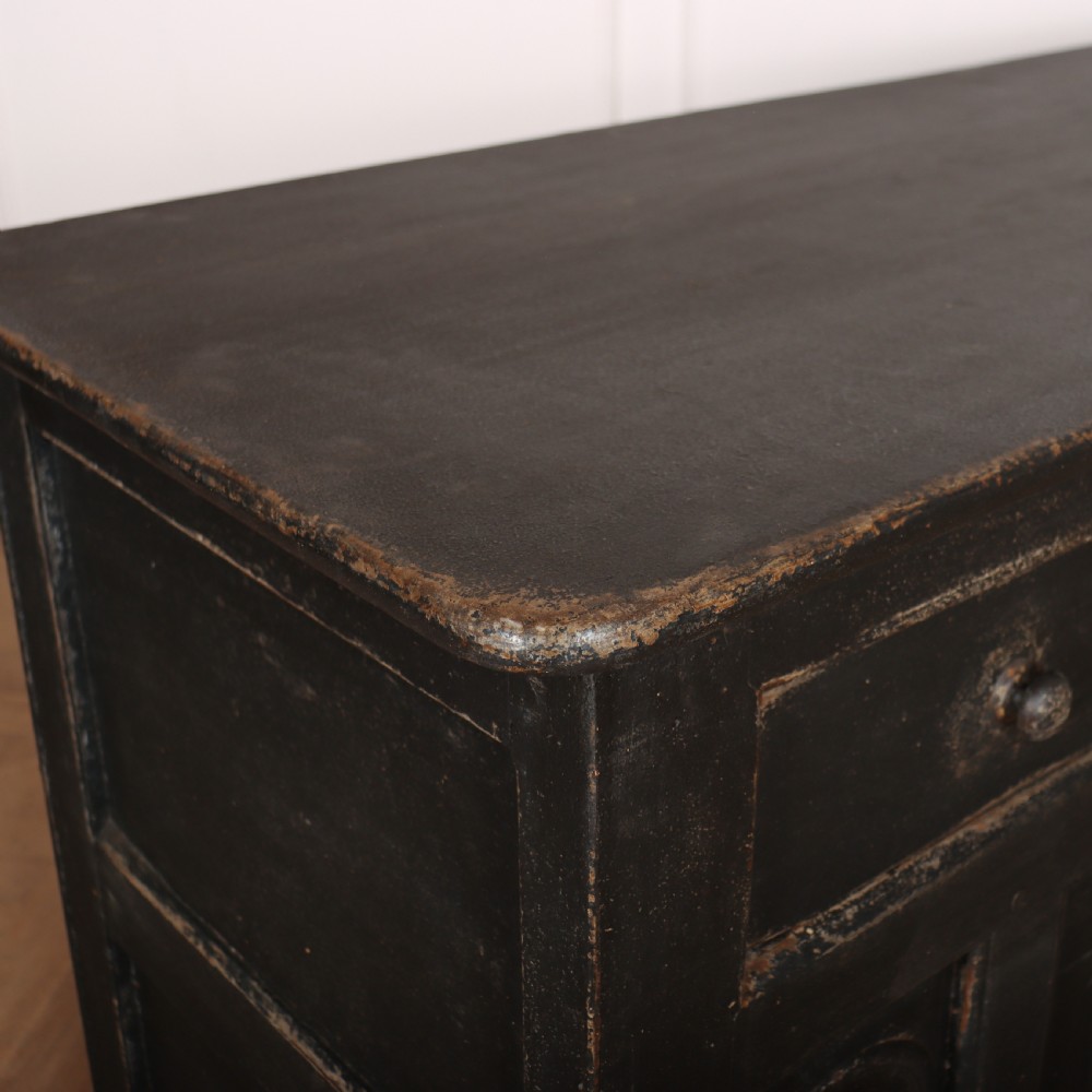 An 18th-century dark painted wooden dresser base featuring four frieze drawers above recessed cupboard doors decorated with geometric arch mouldings. View X