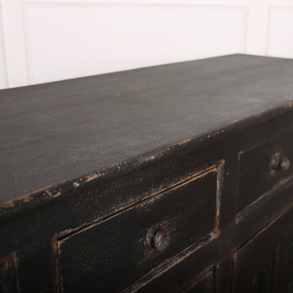 An 18th-century dark painted wooden dresser base featuring four frieze drawers above recessed cupboard doors decorated with geometric arch mouldings. View XI
