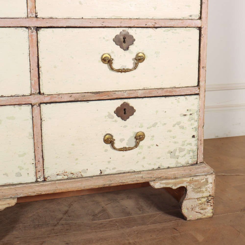 A tall Georgian painted bookcase featuring two multi-pane glazed doors above nine drawers with brass handles. View II