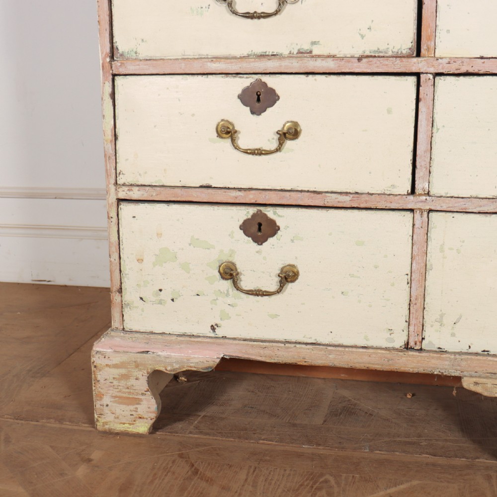 A tall Georgian painted bookcase featuring two multi-pane glazed doors above nine drawers with brass handles. View III