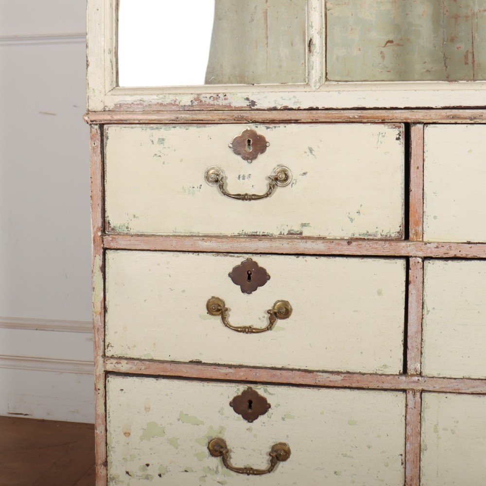 A tall Georgian painted bookcase featuring two multi-pane glazed doors above nine drawers with brass handles. View V