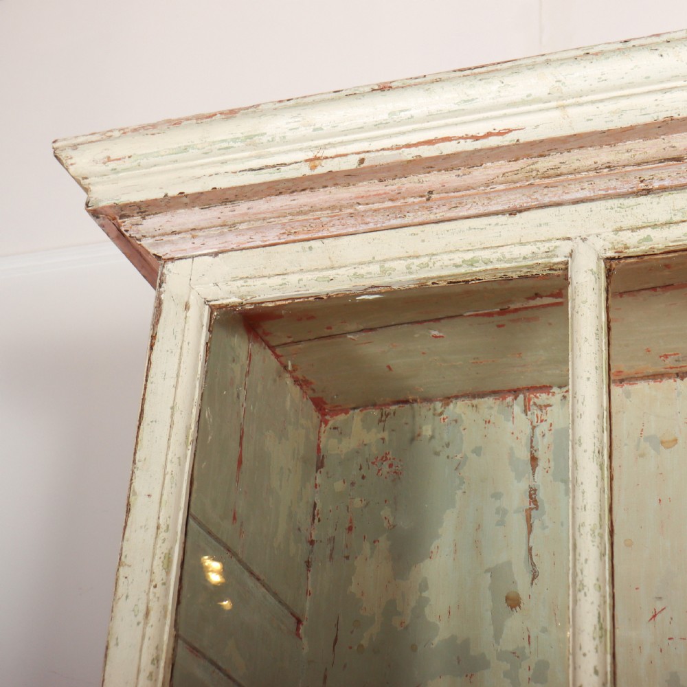 A tall Georgian painted bookcase featuring two multi-pane glazed doors above nine drawers with brass handles. View VI