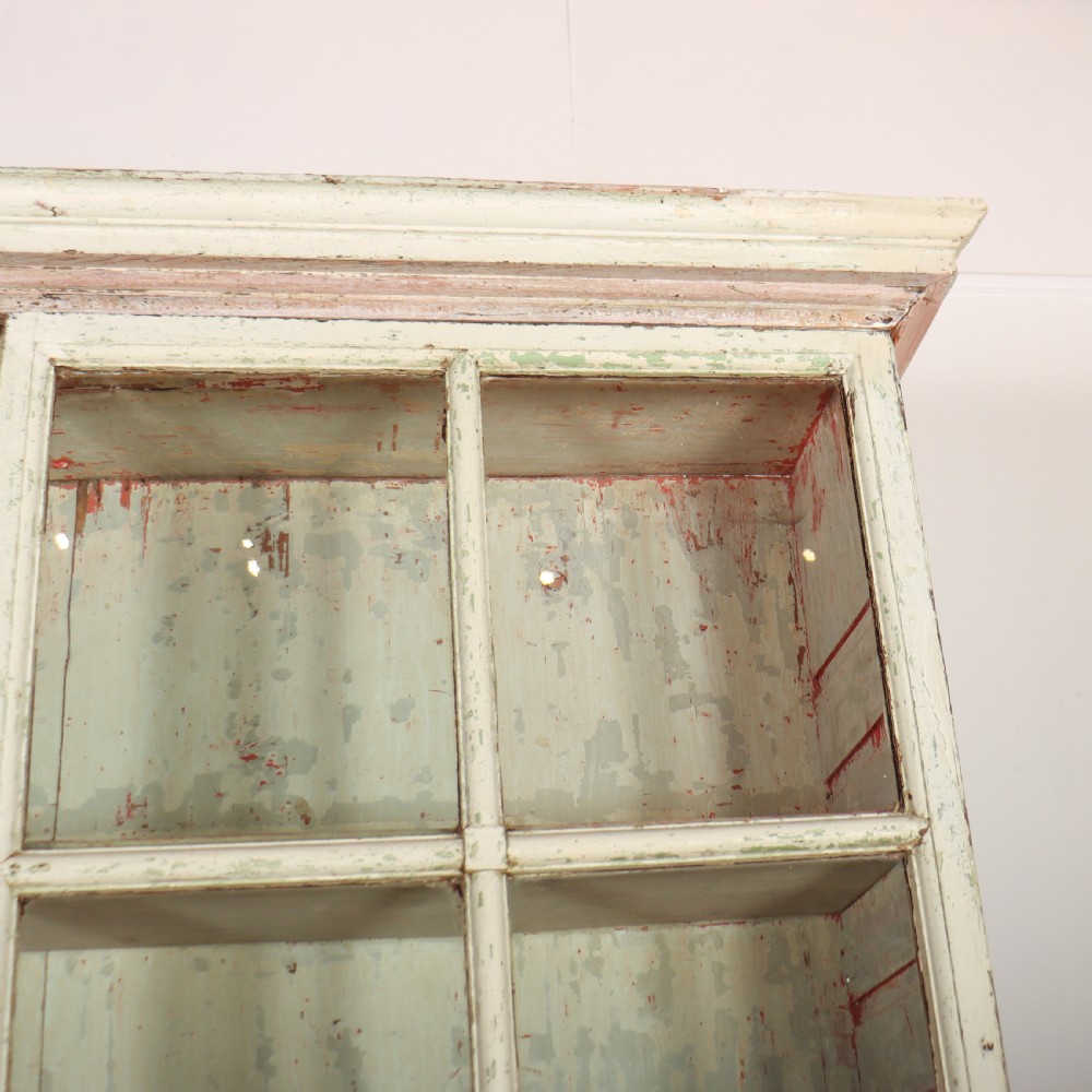 A tall Georgian painted bookcase featuring two multi-pane glazed doors above nine drawers with brass handles. View VIII
