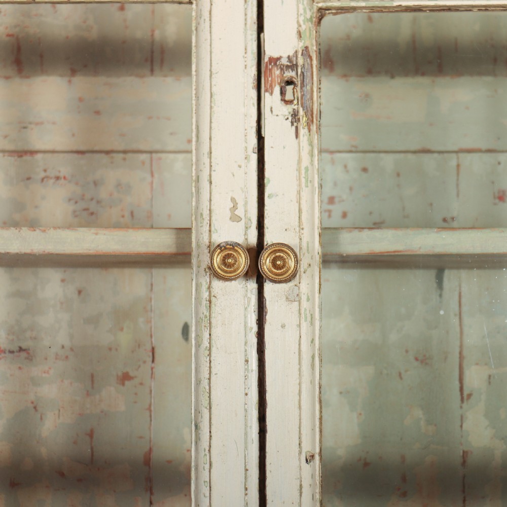A tall Georgian painted bookcase featuring two multi-pane glazed doors above nine drawers with brass handles. View IX
